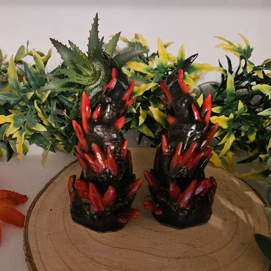 3D-gedruckte Kristallhörner in Schwarz-Rot auf Holzplatte, umgeben von dekorativen Herbstblättern und Kunstpflanzen – fantasievolles Cosplay-Accessoire in einem natürlichen Setting